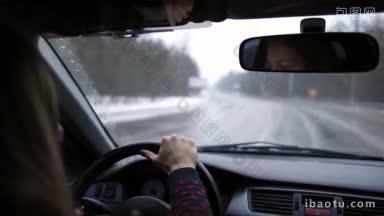 漂亮的年轻女子开车在高速公路上欣赏美丽的风景与雪，享受女司机的气氛